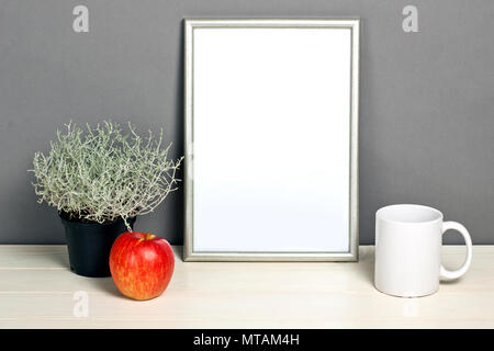 Silver frame Mockup mit Übertopf, Tasse und Apple auf Holzregal. Leeren Rahmen mock up für Presentation Design. Template Rahmen für moderne Kunst. Stockfoto