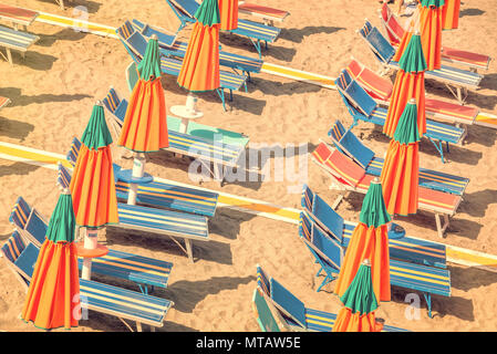 Bunte Liegestühle und Sonnenschirme am Strand von oben, vintage Prozesses gesehen Stockfoto