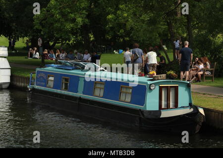 Lifestyle & Boote - Menschen zu Fuß entlang des Ufers am Henley on Thames mit einem Verankerten blauen Kanal Boot im Vordergrund. Copyspace. Stockfoto