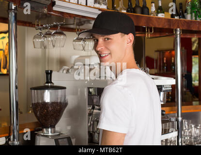 Junge schöne Lächeln barista in weißem Hemd und Baseball Hut s Stockfoto
