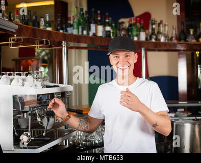 Glücklich lächelnde Barista oder Barkeeper Neben der Kaffeemaschine. Stockfoto