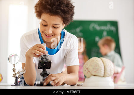 Netter Junge mit einem Mikroskop begeistert Stockfoto