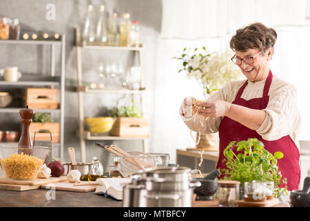 Gerne ältere Frau kochen in Ihre moderne Küche Stockfoto