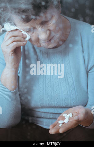 Kranke ältere Frau weinen, holding Pillen in der Hand Stockfoto