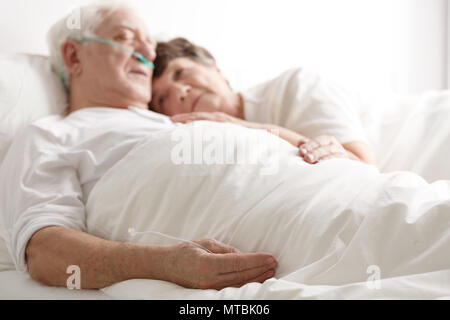 Liebevolle Frau umarmen ernsthaft kranken älteren Mann im Krankenhaus Stockfoto