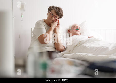 Ältere liebevolle Frau zärtlich die Hand der kranken älteren Menschen Stockfoto