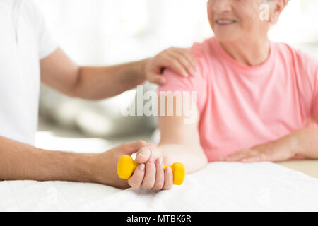 Ältere Patienten Eine aktive, isometrische übung Session mit ihr Physiotherapeut in Pflegeheim verpflichtet Stockfoto