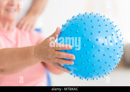 Ältere Frau mit einem großen, Blau, mit Plateausohle massage ball für die Rehabilitation in einem Pflegeheim verwendet wird Stockfoto