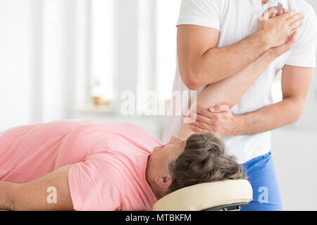 Ältere Patienten ist in ihrer rechten Hand in einem Pnf Übung durch eine Physiotherapeutin gestreckt Stockfoto