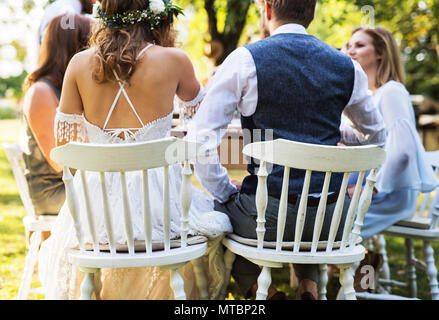 Braut und Bräutigam mit Gästen in Hochzeit außerhalb im Hinterhof. Stockfoto