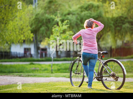 Ältere Frau mit Fahrrad außerhalb im Frühjahr die Natur. Stockfoto