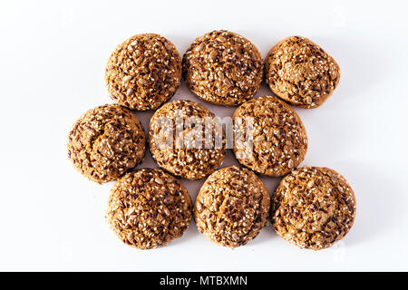 Frisch gebackene Oatmeal cookies sprengte mit Sonnenblumenkernen, Leinsamen und Sesam. Gesundes Gebäck auf einem weißen Hintergrund Stockfoto