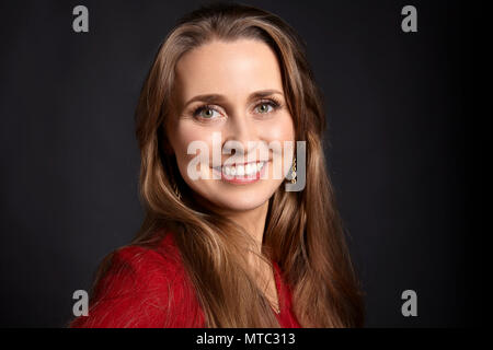 Schließen Portrait von blonde Frau mit langen Haaren, weißes Lächeln und grüne Augen auf schwarzem Hintergrund. Stockfoto
