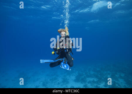 Weibliche Scuba Diver in der Lotus Position hing und wartet vergeht Dekompressionszeit auf Safety Stop im blauen Wasser Stockfoto