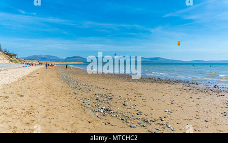 UK, Anglesey, Whitby. 19. Mai 2018. Ein Blick entlang Llanddwyn Beach mit den Bergen von Snowdonia im Hintergrund. Kitesurfer genießen Sie das Wasser. Stockfoto
