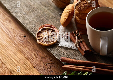 Traditionelle Weihnachten Tee- konzept mit einer Tasse heißen Tee, einen großen Satz von Cookies auf ein homespun Serviette, zimtstangen Bündel, ein paar getrocknete Orangen Stockfoto