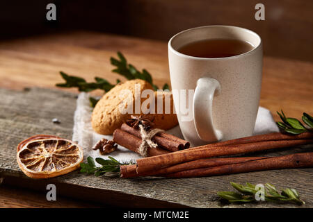 Traditionelle Weihnachten Tee- konzept mit einer Tasse heißen Tee, einen großen Satz von Cookies auf ein homespun Serviette, zimtstangen Bündel, ein paar getrocknete Orangen Stockfoto