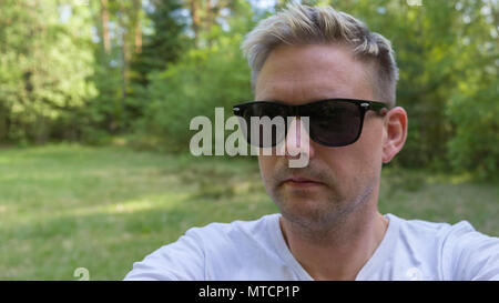 Stattliche Mitte nach 40 s kaukasischen Mann mit schwarzer Sonnenbrille draußen in der Wiese Stockfoto