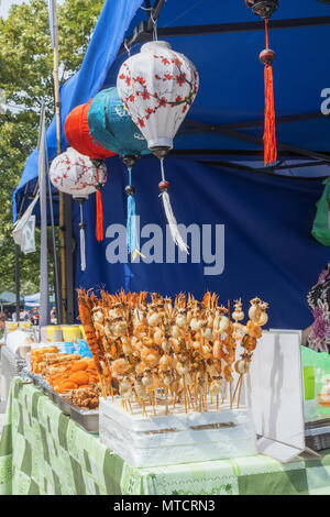 Der Tisch am Kiosk beim Asian Street Food Festival. Die Straßentribüne mit Angebot an asiatischem Essen, bunte chinesische Laternen hingen unter dem Dach eines Zeltes Stockfoto