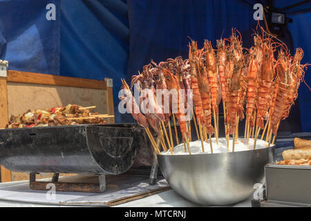 Die Tabelle im Kiosk an der Asiatischen Street Food Festival. Die Straße stand mit Angebot an asiatischen Speisen, Grill mit Kebab und Schüssel mit Meeresfrüchten, Sepia und lobste Stockfoto