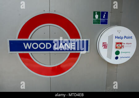 Eine ikonische London U-Bahn name Zeichen für Wood Lane Station montiert auf einer Wand neben einem Help Point. Stockfoto