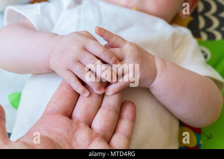 Baby Holding nach übergeordneten Hand, die eine fühlbare Bindung, Vertrauen und Zuneigung, die dem Kind ein Gefühl von Komfort, Sicherheit und Nähe Stockfoto