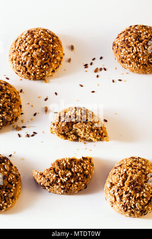 Frisch gebackene Oatmeal cookies sprengte mit Sonnenblumenkernen, Leinsamen und Sesam. Gesundes Gebäck auf einem weißen Hintergrund Stockfoto