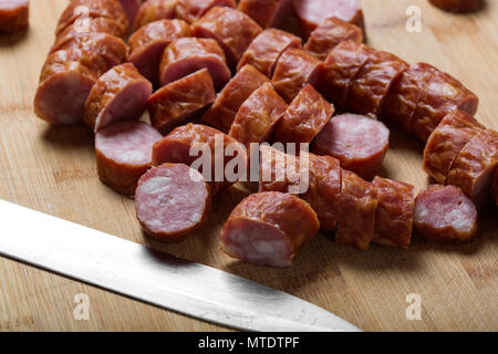 Scheiben geräucherte Wurst aus Schweinefleisch auf einer hölzernen Schneidebrett, Ansicht schließen Stockfoto