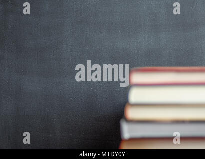 Stapel von Buch vor einer Schiefertafel mit dem Schwarzen Brett im Fokus ruht Stockfoto