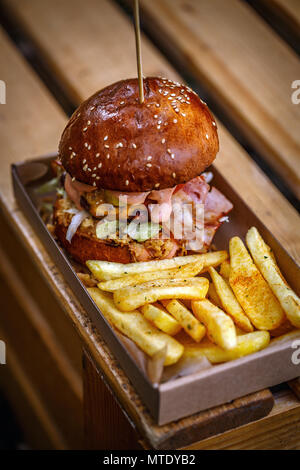 Beefburger mit gebratenen Zwiebeln, Speck und Pommes frites in brioche Bun Stockfoto