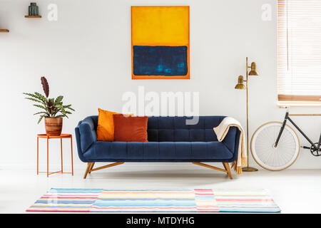 Blau und orange Gemälde hängen an einer weißen Wand über ein elegantes Sofa mit dekorativen Kissen in Wohnzimmer. Real Photo Stockfoto