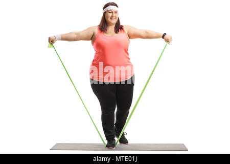 In voller Länge Porträt einer übergewichtigen Frau Training mit einem Gummiband auf einer Matte auf weißem Hintergrund Stockfoto