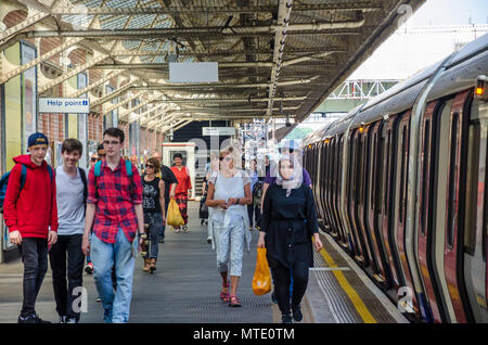 Passagiere Spaziergang entlang der Plattform in der Londoner U-Bahn-Station Hammersmith als ein Zug auf der Plattform wartet. Stockfoto