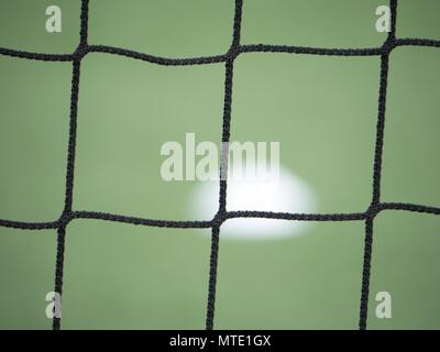 Die Fußball auf grünem Gras durch ein grünes Quadrat Tor net gesehen. Fußball-Ball im Ziel, sport Hintergrund Stockfoto