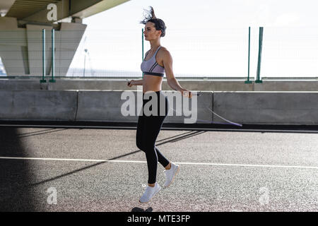Junge Frau springen mit Springseil, Übungen im Freien Stockfoto