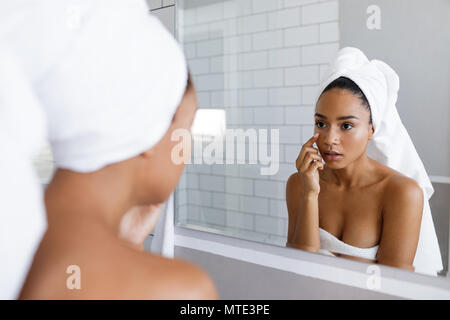 Nahaufnahme von eine attraktive junge Frau, die ihre Haut inspizieren, vor dem Spiegel stehend Stockfoto