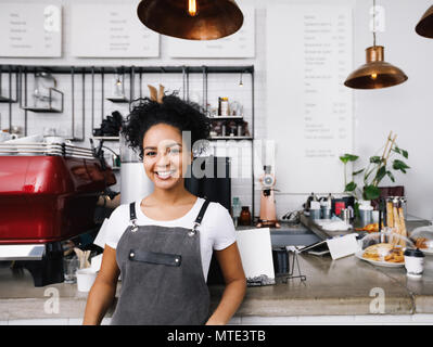 Junge lächelnde barista Schürze tragen, stehen im Cafe Zähler Stockfoto