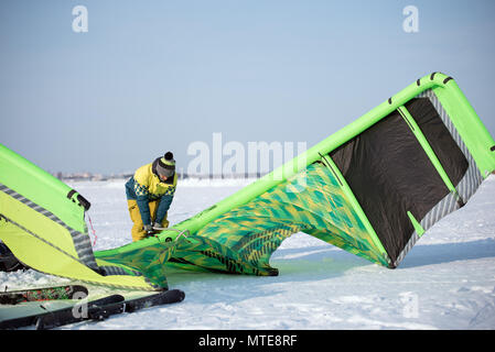 Der Athlet im Winter bereitet einen grünen Drachen für Snowkiting auf der schneebedeckten Feld Stockfoto