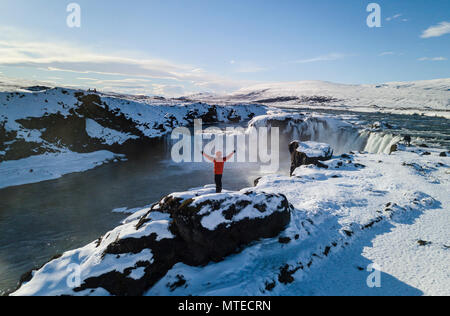 Luftaufnahme, Mann, der vor Wasserfall Góðafoss, Godafoss im Winter mit Schnee und Eis, Norðurland djupivogur Stockfoto