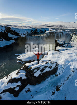 Luftaufnahme, Mann, der vor Wasserfall Góðafoss, Godafoss im Winter mit Schnee und Eis, Norðurland djupivogur Stockfoto