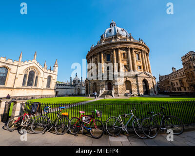 Fahrräder auf Geländer außerhalb Radcliffe Camera, mit All Souls College, Universität Oxford, Oxford, Oxfordshire, England, UK, GB. Stockfoto