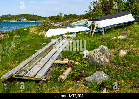 Kleine entspannende Boote liegen auf dem Trockenen an einem sonnigen Tag. Teil eines hölzernen Pier neben Ihnen liegen. Stockfoto