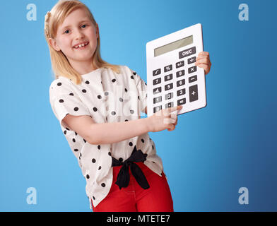 Gerne moderne Kind in roten Hosen сlicking auf die Taste auf dem Taschenrechner auf blauem Hintergrund Stockfoto