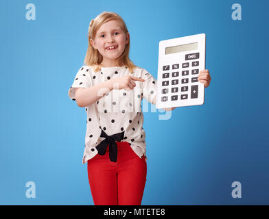 Gerne moderne Kind in roten Hosen am Rechner isoliert auf Blau zeigen Stockfoto
