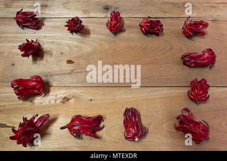 Roselle (Hibiscus sabdariffa) Magenta Farbe calyces (sepalen) Rahmen auf Holztisch, Hintergrund, flach Stockfoto