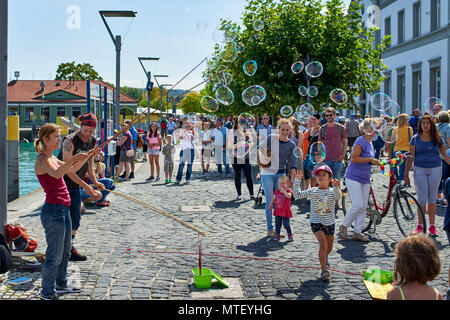 Paar Animateure unterhalten die Kinder und öffentliche Seifenblasen auf dem Platz in Konstanz Stockfoto