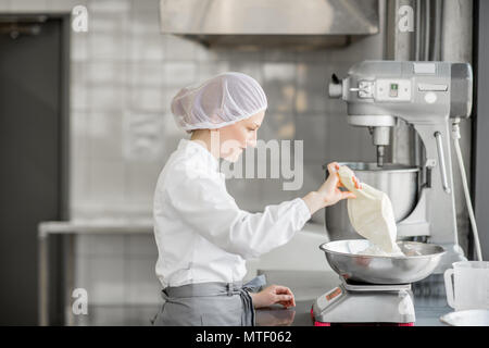 Frau Konditor in Uniform wiegen Zutaten für Gebäck in der Bäckerei verarbeitenden Gewerbe Stockfoto