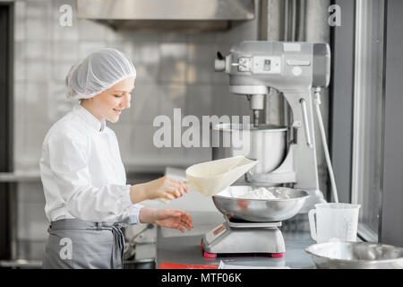 Frau Konditor in Uniform wiegen Zutaten für Gebäck in der Bäckerei verarbeitenden Gewerbe Stockfoto