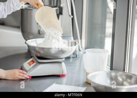 Frau Konditor in Uniform wiegen Zutaten für Gebäck in der Bäckerei verarbeitenden Gewerbe Stockfoto