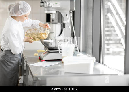 Frau Konditor in Uniform wiegen Zutaten für Gebäck in der Bäckerei verarbeitenden Gewerbe Stockfoto